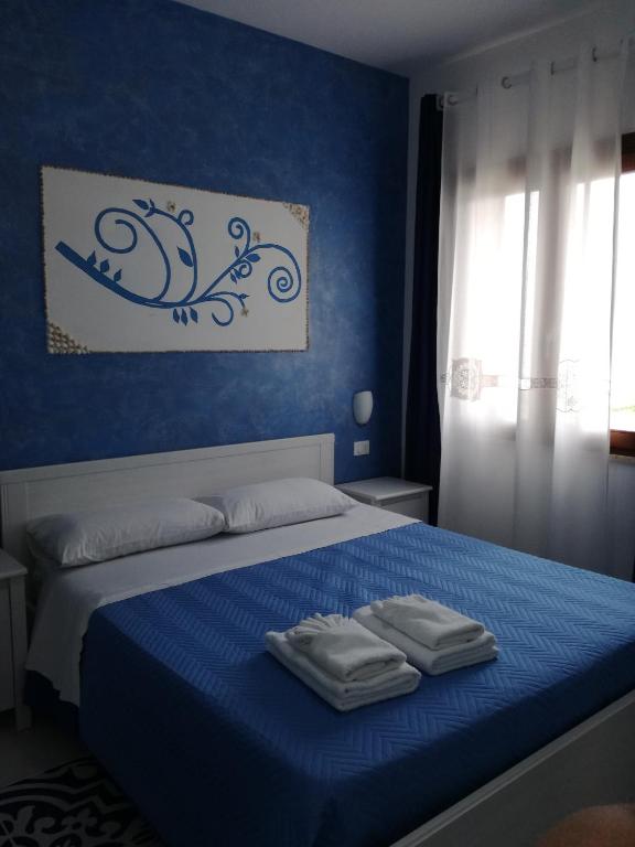 a blue bedroom with a bed with two towels on it at Benvenuti al Sud B&B in Macari