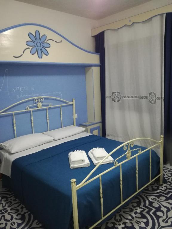 a bedroom with a blue bed with towels on it at Benvenuti al Sud B&B in Macari