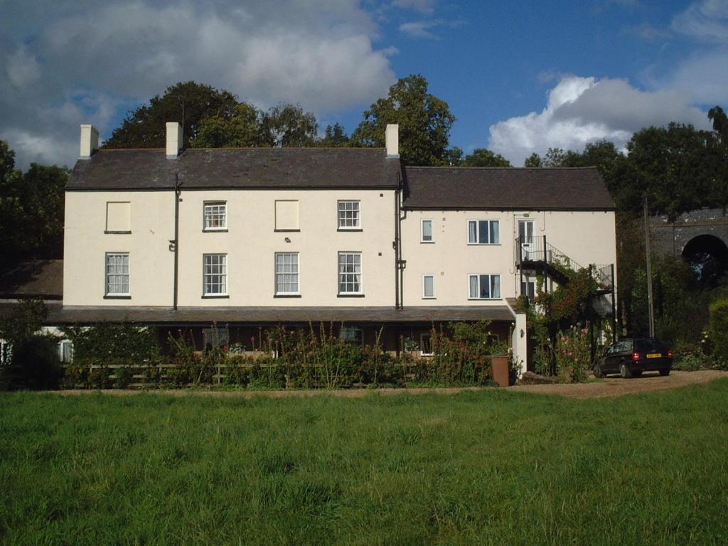 a large white house sitting on top of a green field at Murcott Mill in Long Buckby