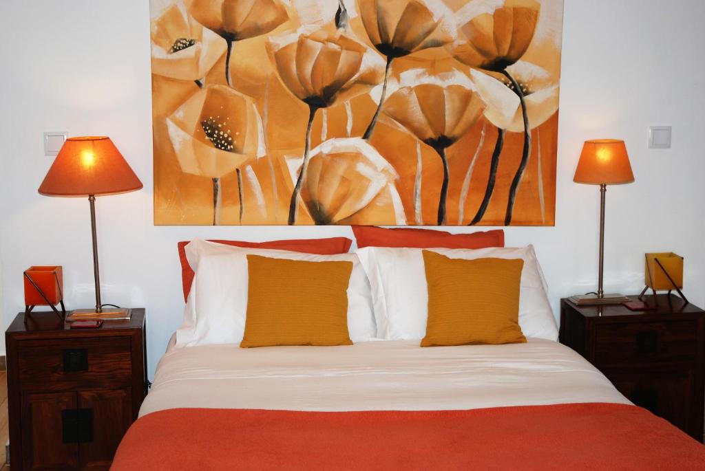a bedroom with a bed with a painting on the wall at Stressfree Suite in Vila Nova de Milfontes