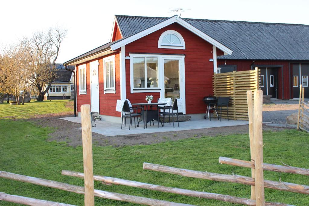 ein rotes Haus mit einem Tisch, Stühlen und einem Zaun in der Unterkunft Smeakalles in Tvååker