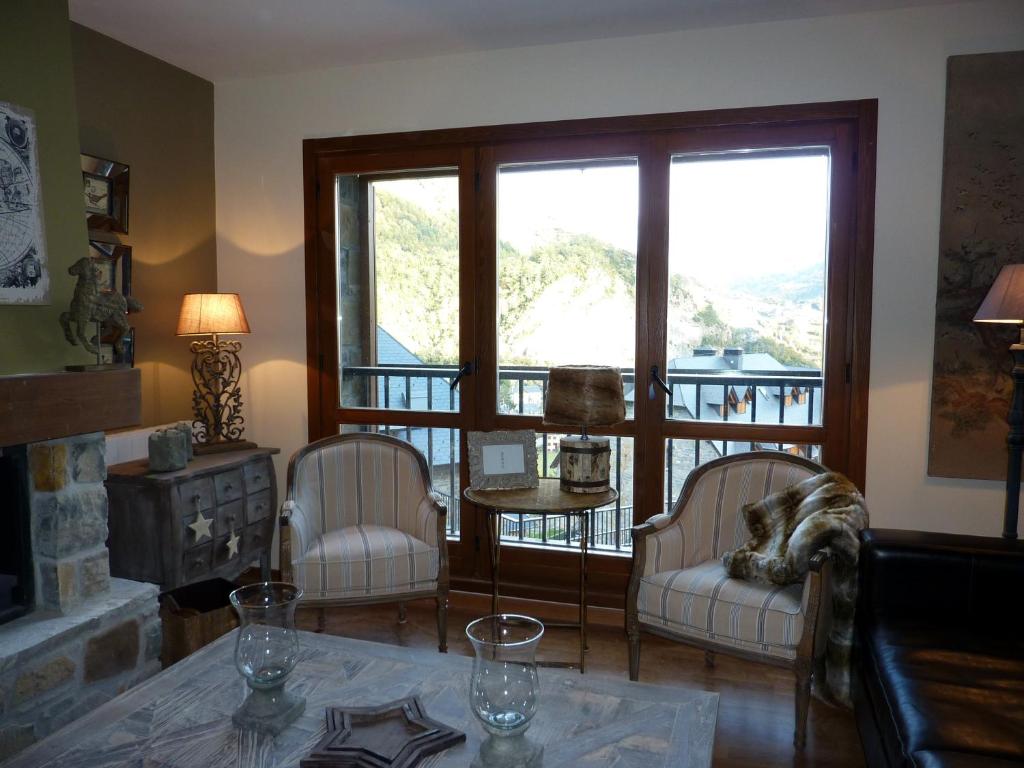 a living room with two chairs and a table and a window at Los Altos de Escarrilla - tucasaenlospirineos in Escarrilla