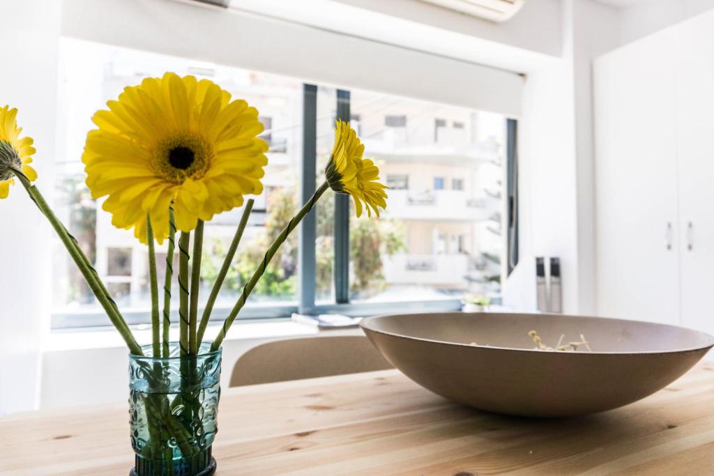 un vaso con fiori gialli e una ciotola su un tavolo di Urban Studios a Rethymno