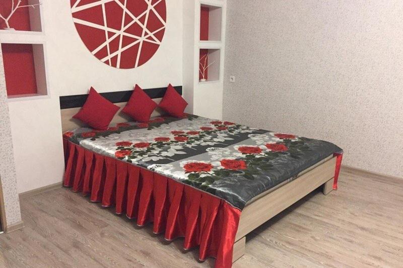 a bedroom with a bed with red pillows at Apartment on Dzerzhinskogo 62 in Tyumen
