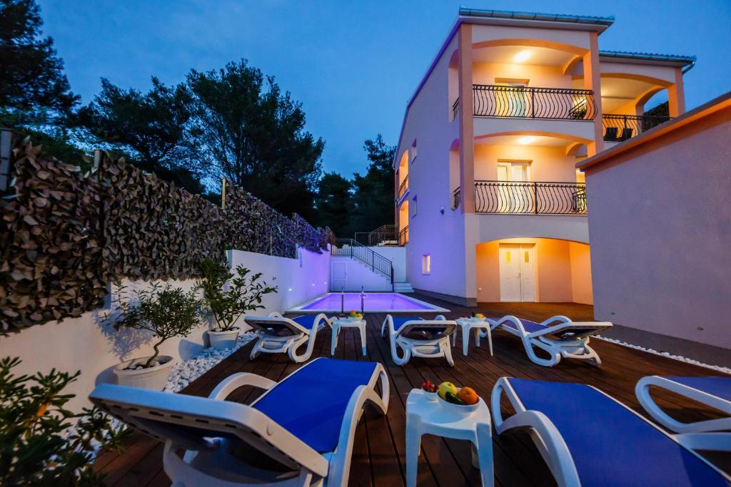 un patio con sillas azules y blancas y un edificio en Villa Nora, en Trogir