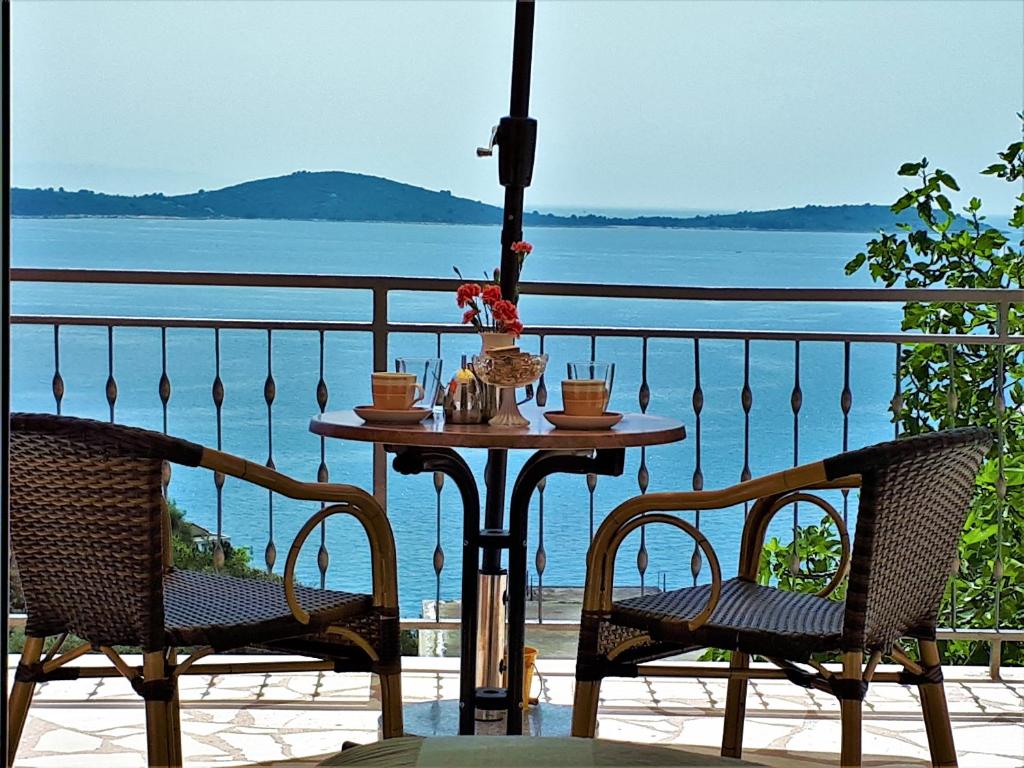 een tafel en stoelen op een balkon met uitzicht op het water bij Apartments T&M in Vinišće
