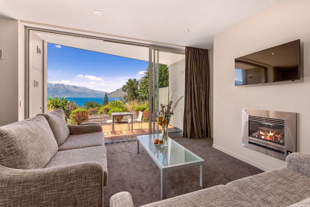 a living room with a fireplace and a view of the water at Highview Apartments in Queenstown