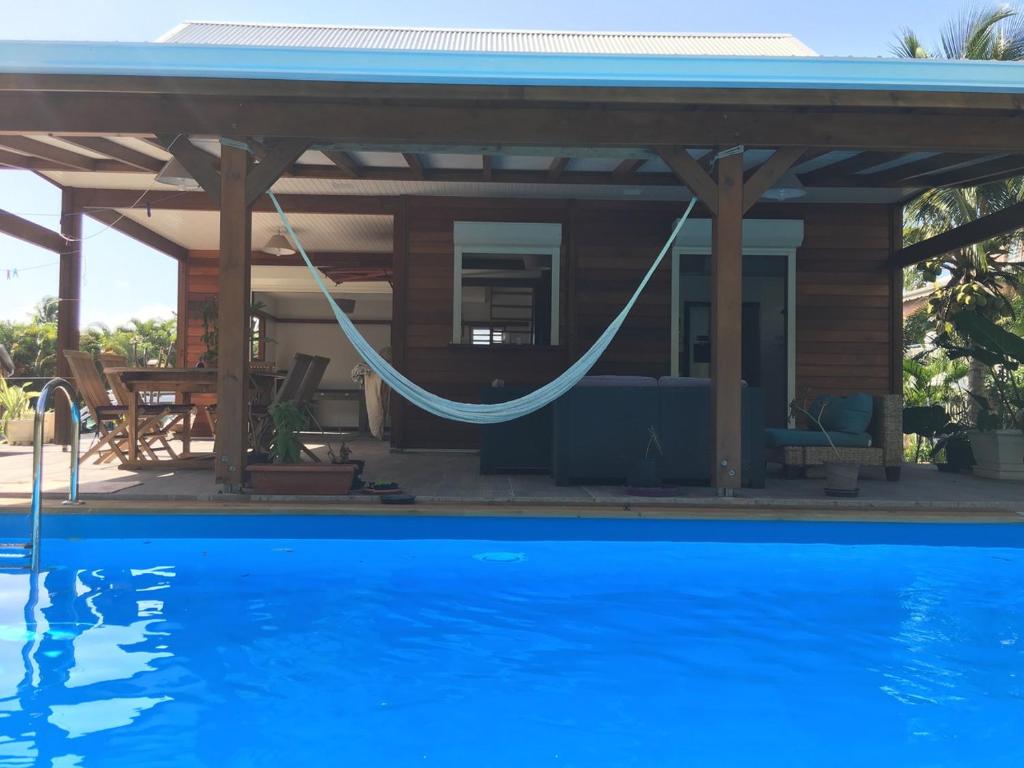 ein Haus mit einer Hängematte und einem Pool in der Unterkunft Villa avec piscine in Saint-François