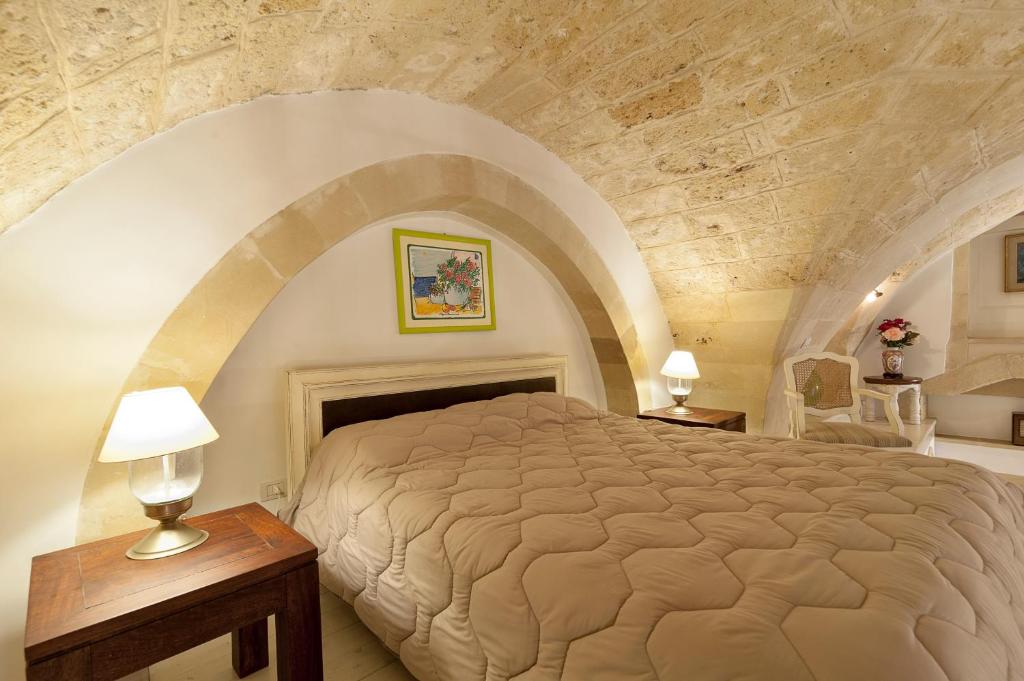 レッチェにあるSuite dei Baroniの石壁のベッドルーム1室(大型ベッド1台付)