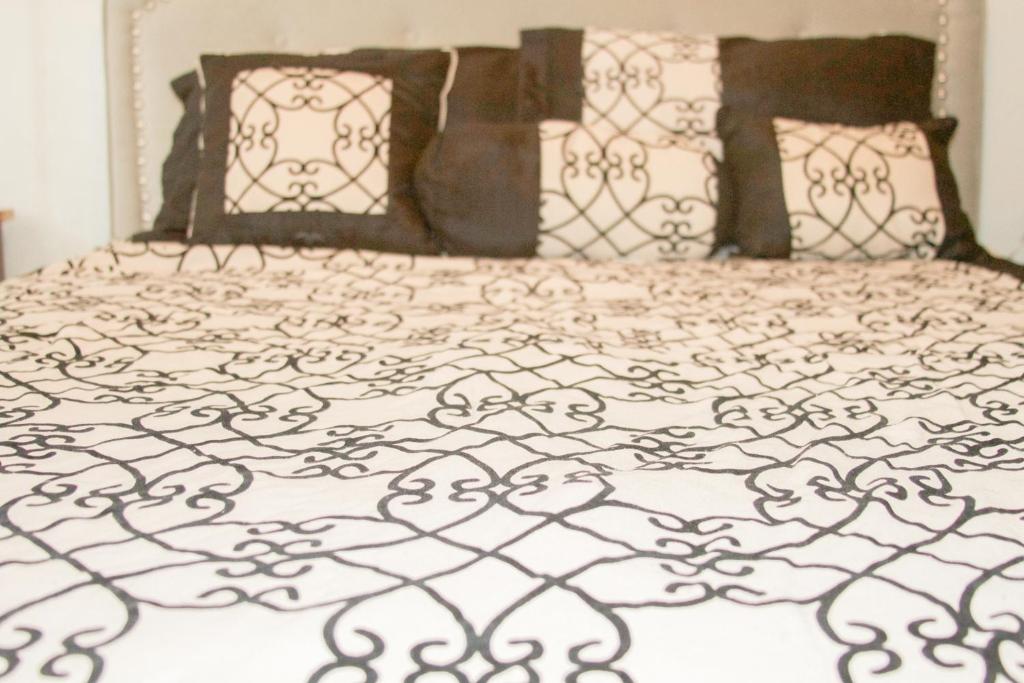 uma cama com um edredão e almofadas preto e branco em 2 BEDROOM / 1 BATH ONLY 5 MINUTES AWAY FROM BANK OF HAWAII em Sinajana