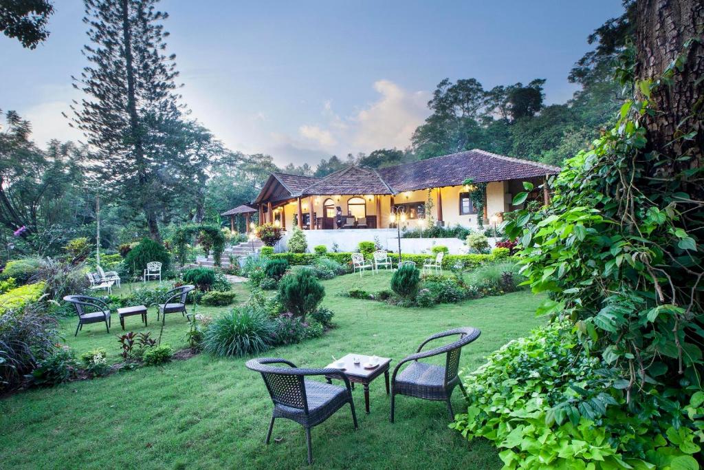 a house with chairs and a table in the yard at Old Kent Estates & Spa, Coorg in Suntikoppa