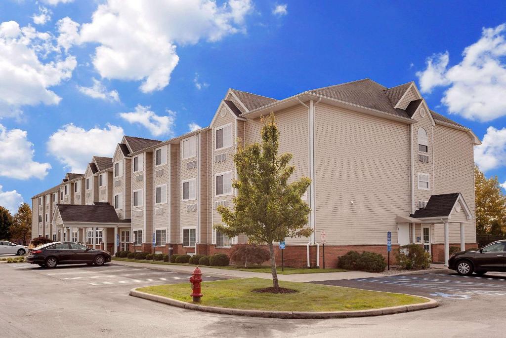 a large apartment building with a tree in a parking lot at Microtel Inn & Suites by Wyndham Middletown in Middletown