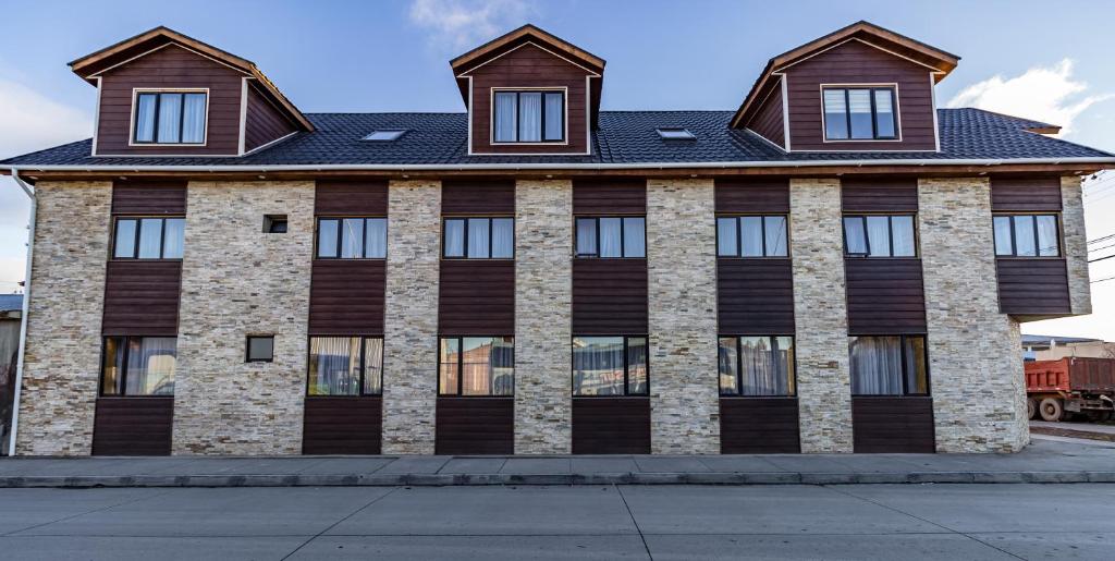 ein großes Backsteingebäude mit schwarzem Dach in der Unterkunft Cabañas Última Esperanza in Puerto Natales