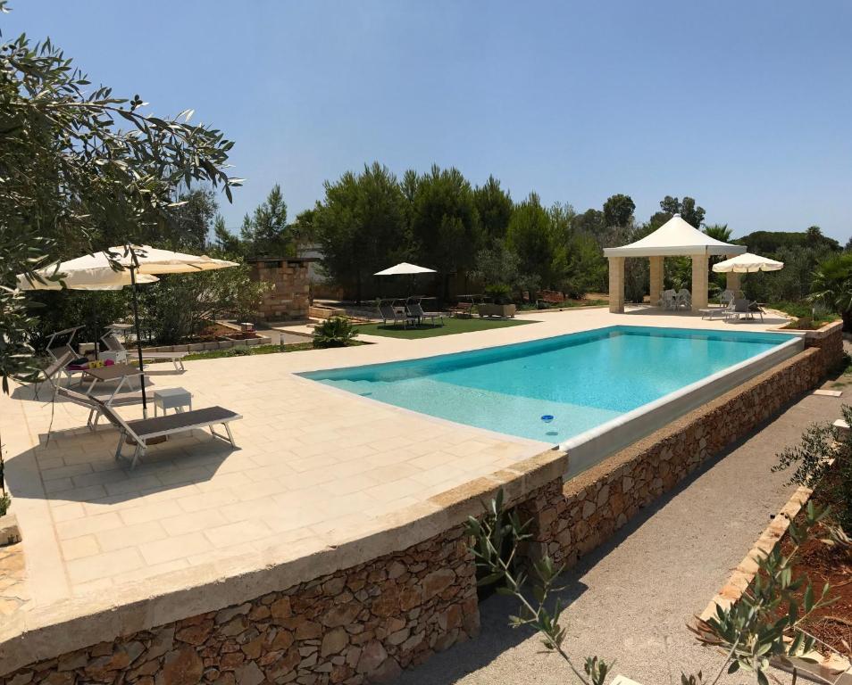 una piscina in un resort con tavolo e ombrelloni di WHITE POOL Matino - Gallipoli - 7pl a Matino