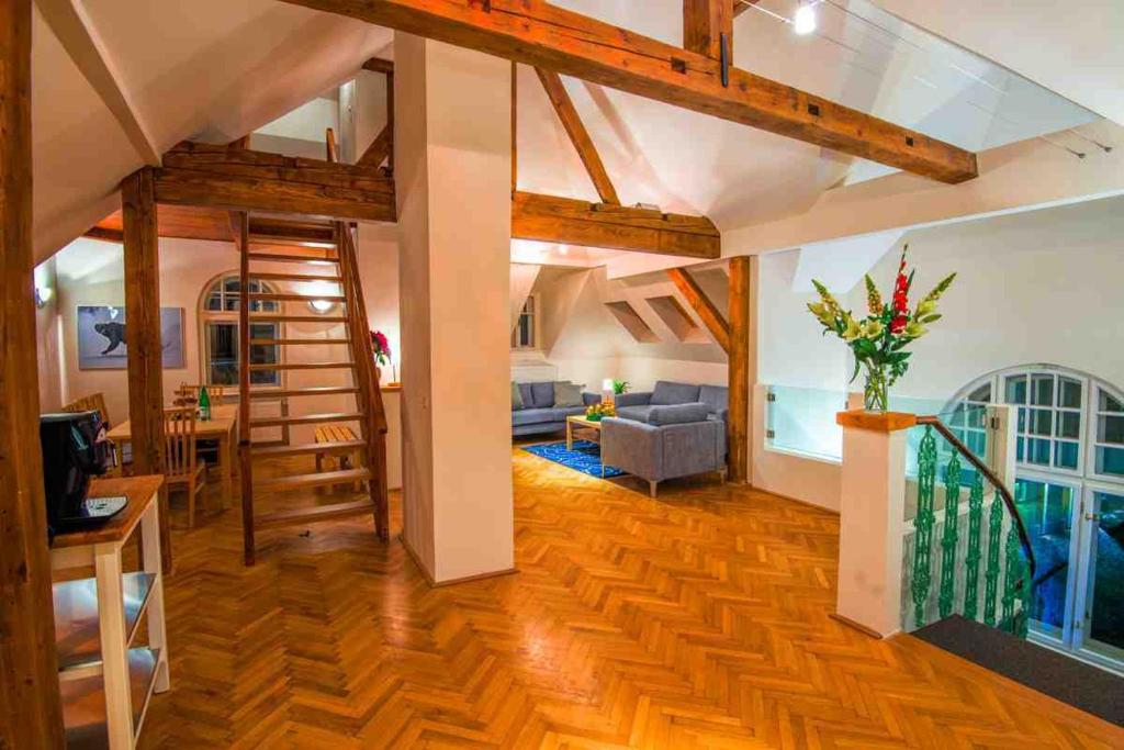 duży salon z drewnianą podłogą i schodami w obiekcie CasaNeve w mieście Bad Gastein