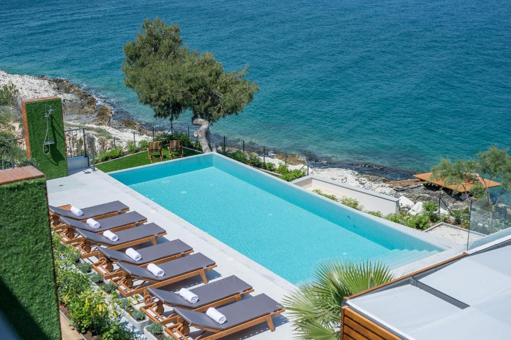 a swimming pool with lounge chairs next to the ocean at Olive Hill House in Slatine