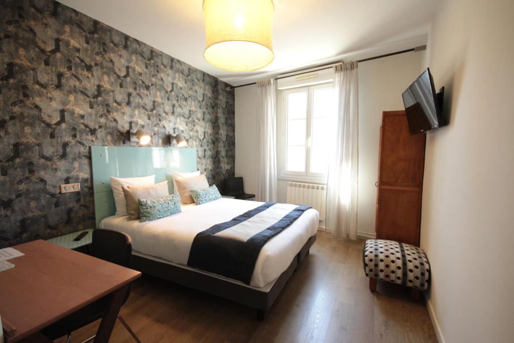 1 dormitorio con cama, mesa y TV en Hôtel Des Arts, Artisanal et Indépendant en Montpellier