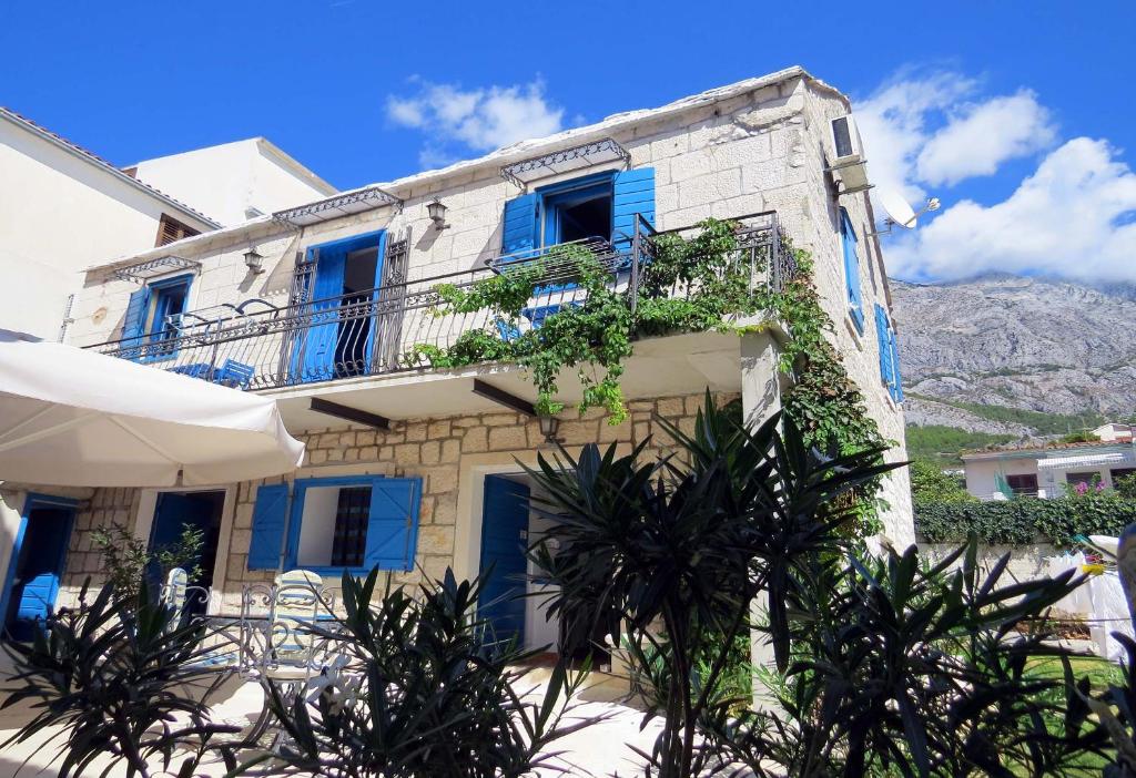 a building with blue doors and trees in front of it at PKM Apartments Baska Voda in Baška Voda