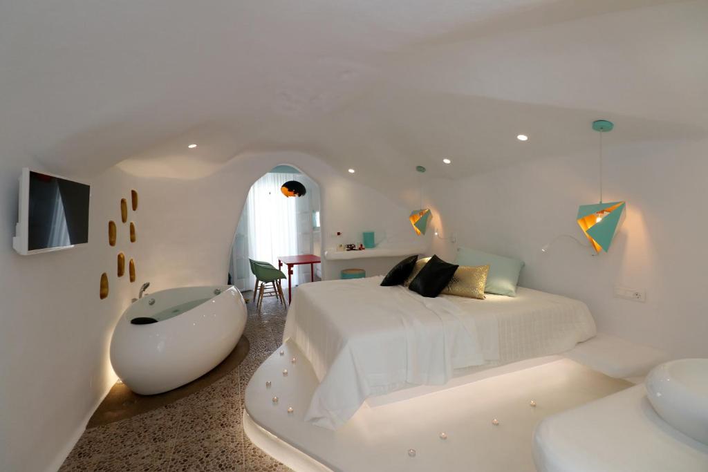 Habitación blanca con cama blanca y bañera en Naxos Cave Suites en Stelida
