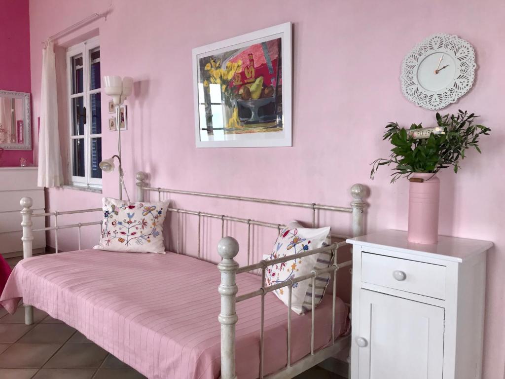 een roze slaapkamer met een bed met een roze muur bij Vlichos Studio Apartment in Hydra