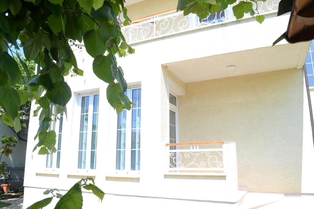 a white house with a balcony and windows at Open Doors Bed & Breakfast in Shkodër