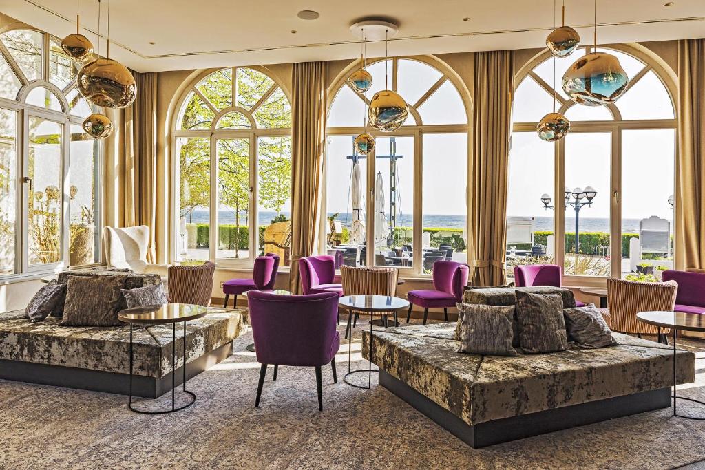 a lobby with purple chairs and tables and windows at SEETELHOTEL Strandhotel Atlantic in Bansin