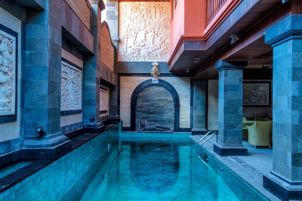 a swimming pool in a building with an archway at Murni's Houses & Spa in Ubud
