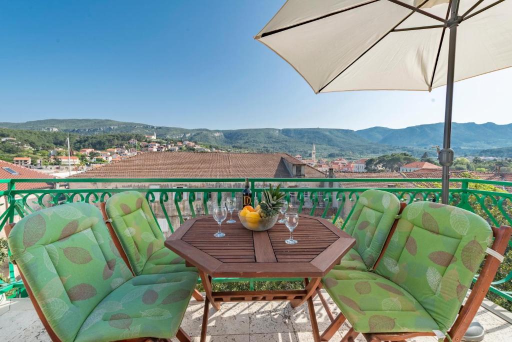 einen Tisch mit Stühlen und einem Sonnenschirm auf dem Balkon in der Unterkunft Apartments Napoleon in Jelsa