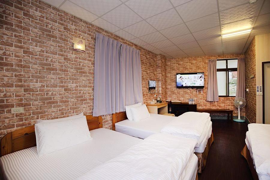 a room with three beds and a brick wall at Zhongshan Hostel in Fenqihu