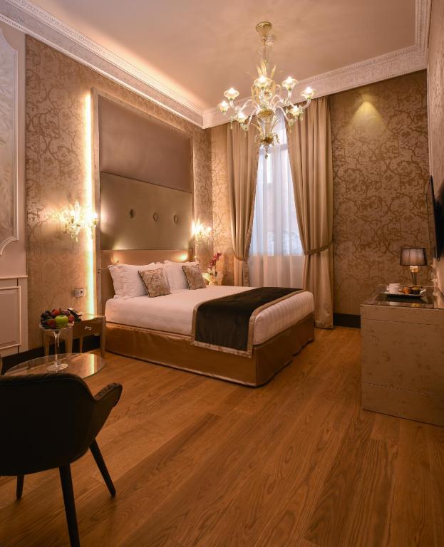 sypialnia z dużym łóżkiem i żyrandolem w obiekcie Santa Croce Boutique Hotel w Wenecji