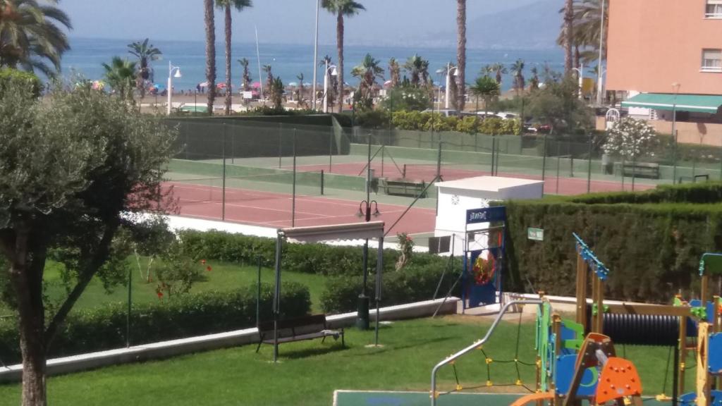 un parc avec une aire de jeux et un court de tennis dans l'établissement Primera línea de playa. Magnífica urbanizacion, à Cala del Moral