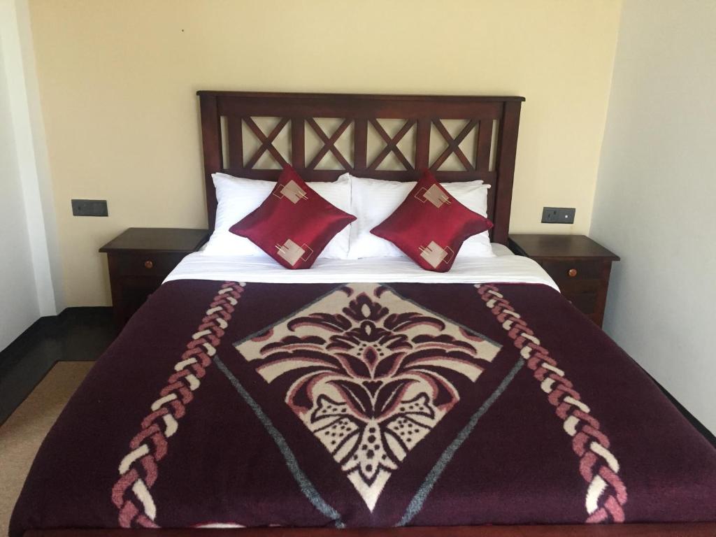 a bed with a wooden headboard with red pillows at Suriya Guest in Nuwara Eliya