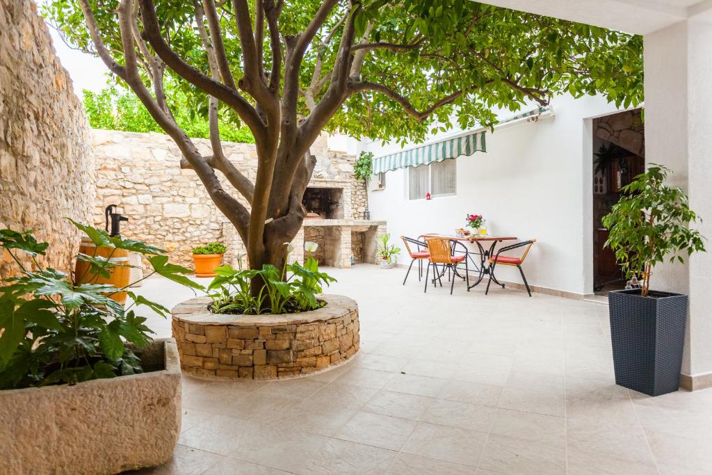 un patio con un árbol, una mesa y sillas en Guest House Mara, en Vela Luka