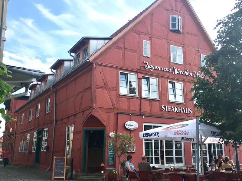 un edificio rojo con gente sentada fuera de él en Märchenhotel, en Bergen auf Rügen