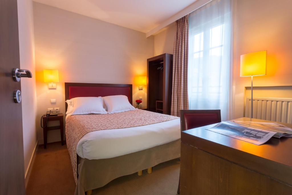 um quarto de hotel com uma cama, uma secretária e uma janela em Le Home em Vincennes