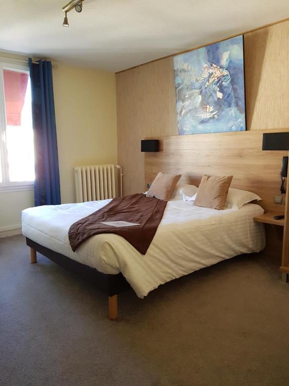 a bedroom with a large bed with a painting on the wall at Hôtel L'Univers in Châtellerault
