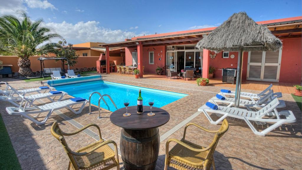 un patio con mesa, sillas y piscina en Villa Romana, en Caleta de Fuste