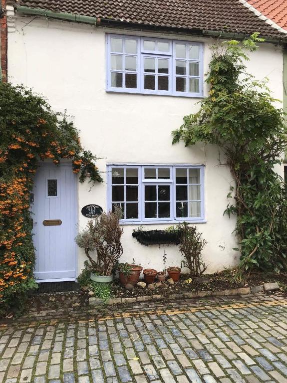 a white house with a white door and potted plants at Lavender Cottage in Yarm