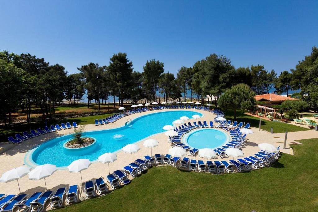 uma imagem de uma piscina com cadeiras e guarda-sóis em Hotel Aurora Plava Laguna em Umag