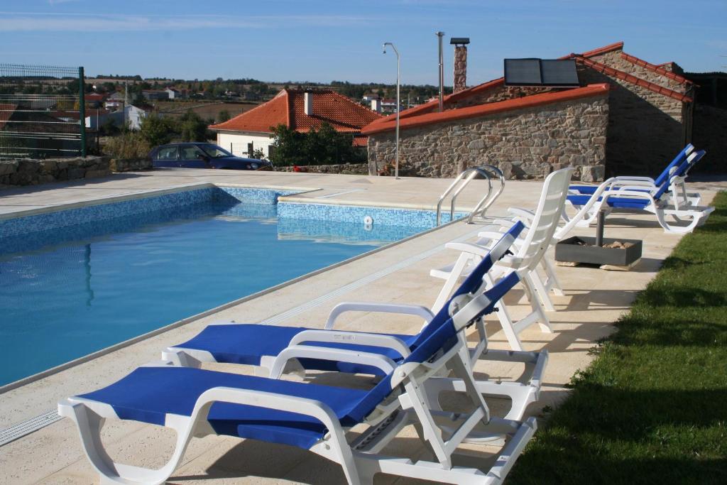 a row of lounge chairs next to a swimming pool at Quinta de la Barandica in Miranda do Douro