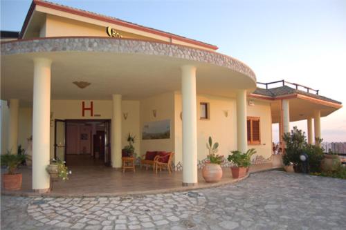 ein großes Haus mit einer Veranda auf der Vorderseite mit einer Terrasse in der Unterkunft Hotel La Cometa in Diamante