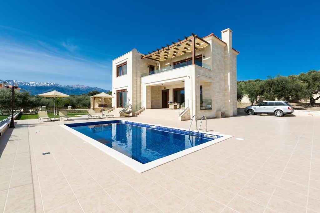 a villa with a swimming pool in front of a house at Rodi Stone Villa in Kalyves