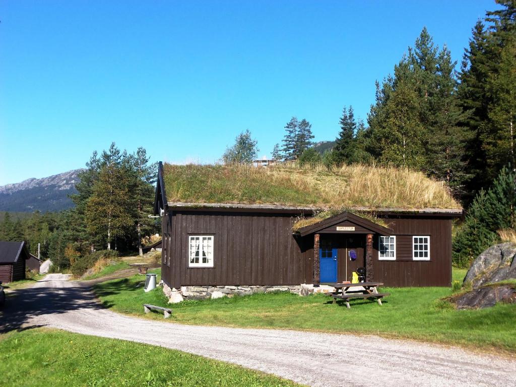 Tuddal的住宿－Hogstul Hytter - Gamlestua，带有草地屋顶的建筑,有碎石路
