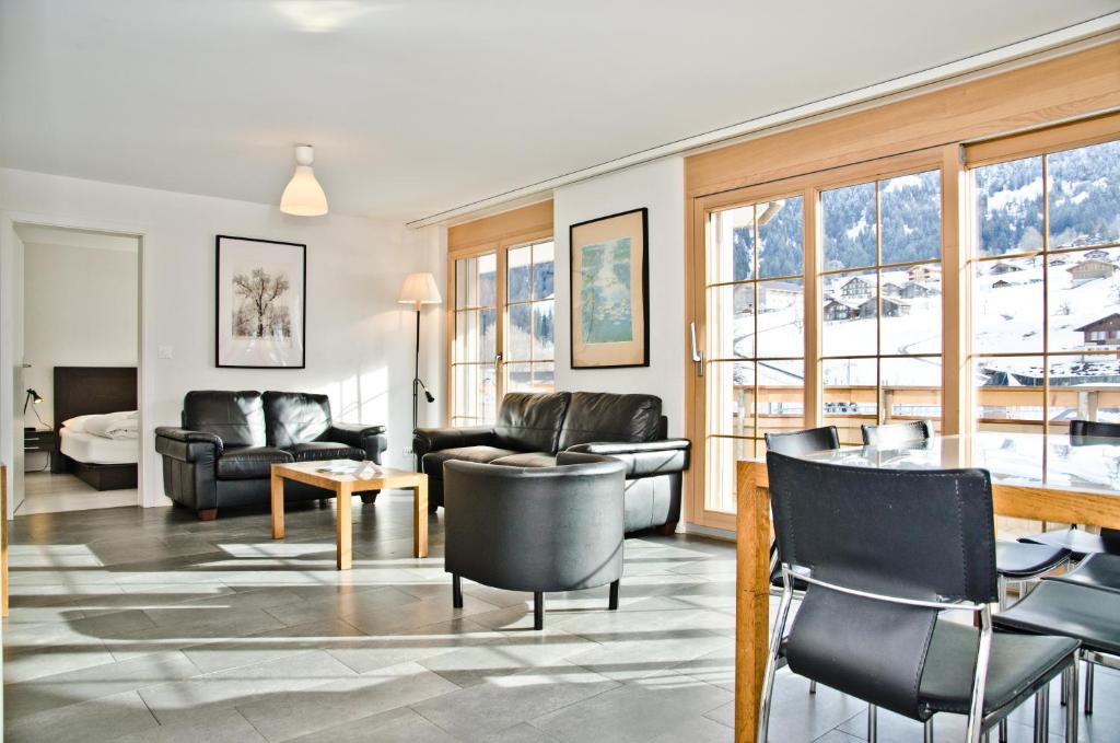 ein Wohnzimmer mit einem Sofa, einem Tisch und Stühlen in der Unterkunft Apartment Alpha - GRIWA RENT AG in Grindelwald