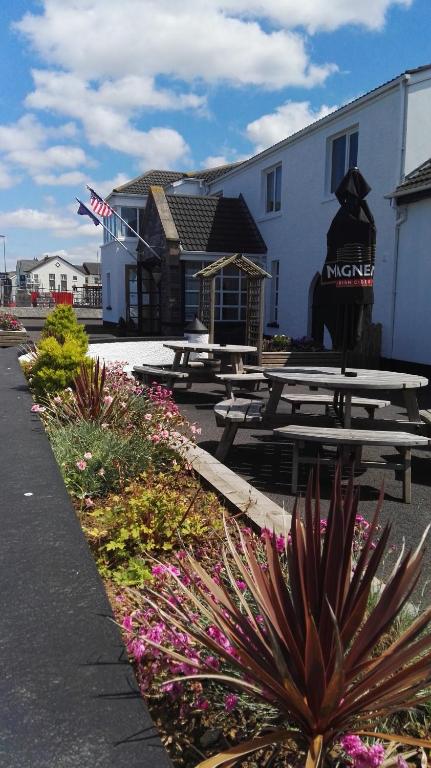 a group of picnic tables in front of a building at Inn On The Coast in Portrush