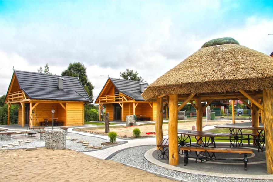 un grupo de cabañas de madera con bancos y mesas en Bacówki nad jeziorem Goszcza en Lubrza