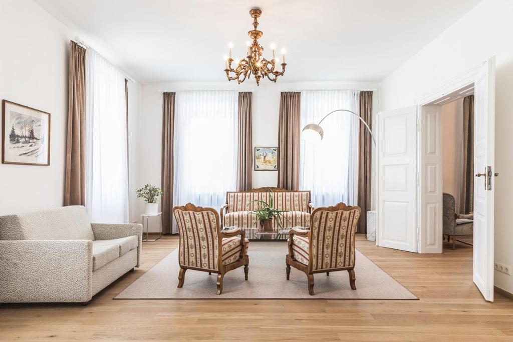 a living room with a couch and chairs and a chandelier at Sandwirth Suites Palais Musil in Klagenfurt