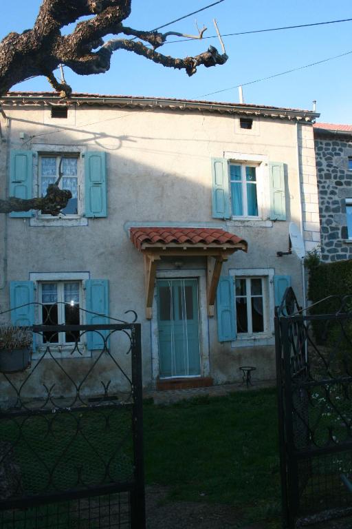 una casa con ventanas azules y una valla delante de ella en Gite familial à proximité d'une mini ferme en Saint-Haon