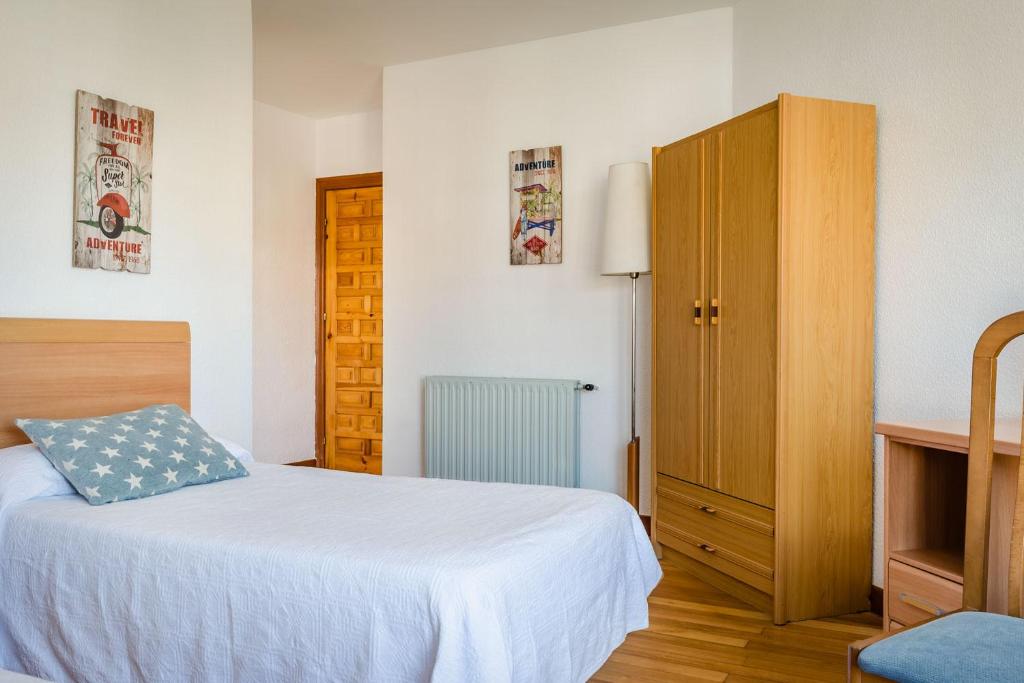 1 dormitorio con 1 cama y armario de madera en Hotel Surfances, en Suances