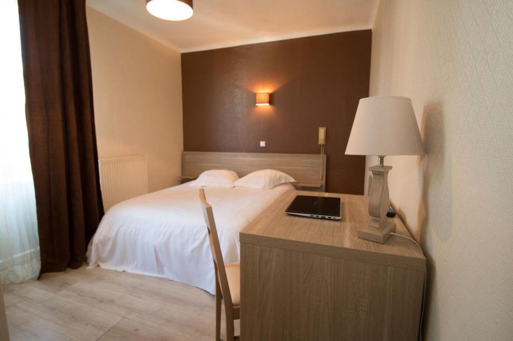 a bedroom with a bed and a desk with a lamp at Hôtel Pacific in Calais